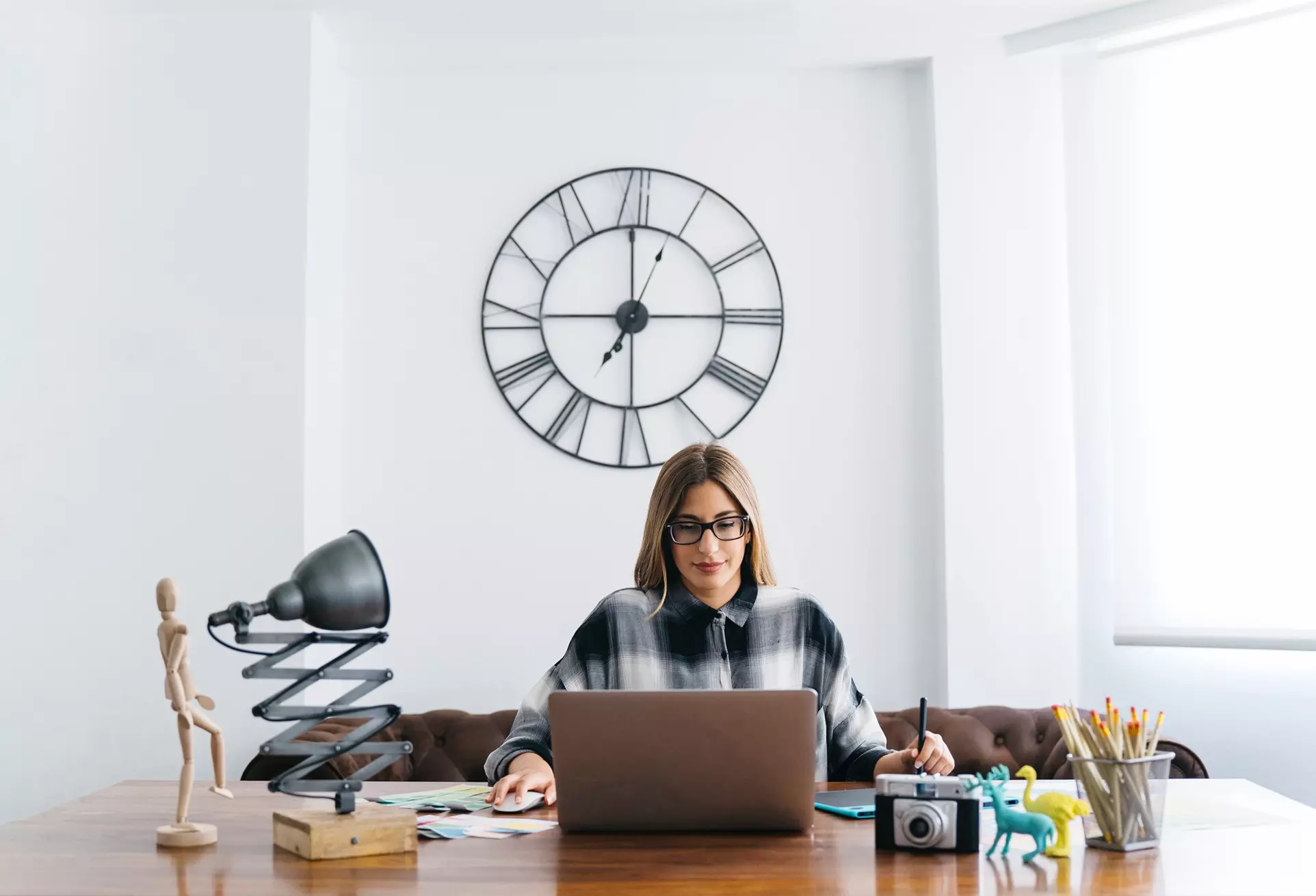 Woman is working overtime hours in the office where the clock is above her head showing that she works long hours giving an idea about the new overtime rules from DOL FLSA