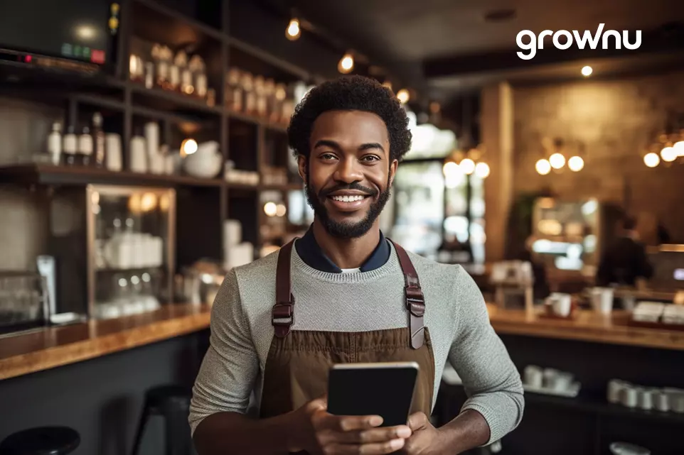 A nice looking and self confident afro american barista and small caffee owner standing with the tablet in his hand representing the workforce management solutions idea for restaurant business